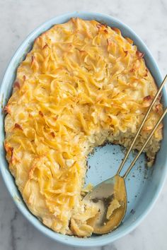 a blue bowl filled with macaroni and cheese on top of a marble counter