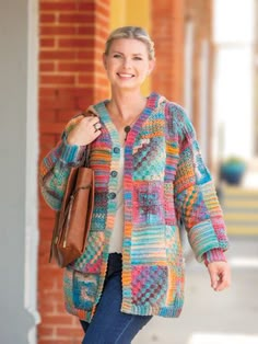 a woman is walking down the street wearing a colorful cardigan and carrying a brown bag