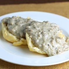 two biscuits covered in gravy on top of a white plate