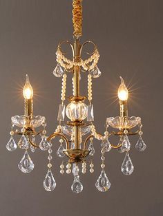 a gold chandelier with crystal drops hanging from it's center and two lights on each side