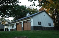 two garages on the side of a grassy hill with trees in the back ground