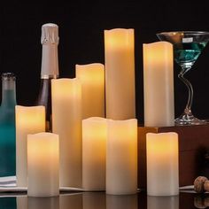 many lit candles on a table next to bottles