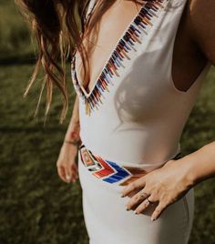 a woman in a white dress is standing on the grass with her hands behind her back