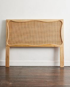 a wooden headboard against a white wall in an empty room with wood flooring