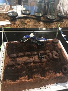 a large chocolate cake sitting on top of a counter next to some dirt bike tires