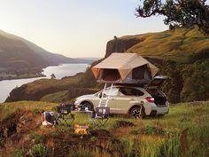 a car parked on top of a lush green hillside next to a body of water