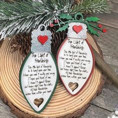 two christmas ornaments sitting on top of a piece of wood