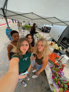 three women taking a selfie at an outdoor market with flowers and plants on display