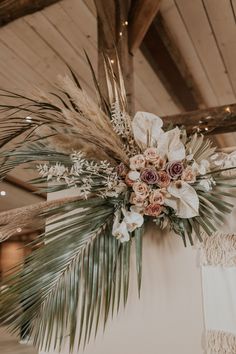 an arrangement of flowers and greenery hangs from the ceiling in a rustic wedding venue