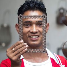 a man holding up a piece of metal in front of his face with chains on it