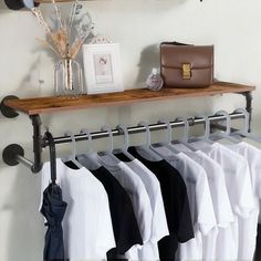 a rack with clothes hanging on it next to a purse