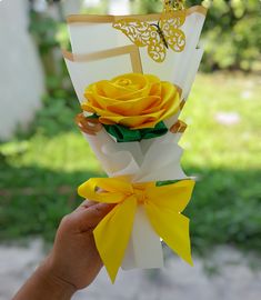 a hand holding a bouquet of yellow roses in it's left side, with a butterfly on the top