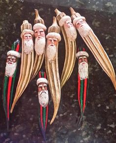 five wooden santa claus heads are lined up on a marble counter top with long green and red tails