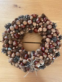 a wreath made out of pine cones and acorns on a wooden table top