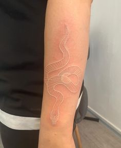 a woman's arm with a white snake tattoo on the left side of her arm