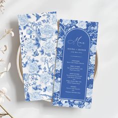 a blue and white floral wedding program on a plate with flowers in the foreground