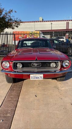 an old red car parked in front of a fence