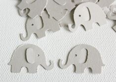 several elephant cutouts are shown on a white surface with grey paper in the background