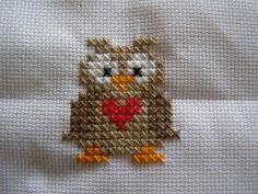 a cross stitch owl with a heart on it's chest