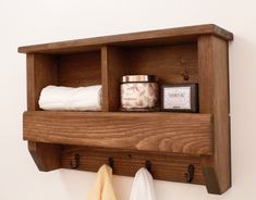 a wooden shelf with two shelves holding towels and other bathroom items on top of it