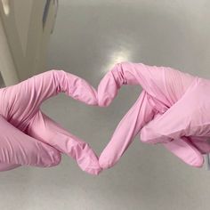 two hands in pink gloves making a heart shape