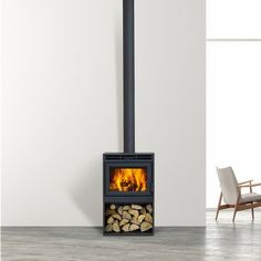 a fire place with logs in it and a chair next to it on the floor