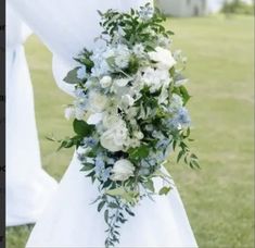 a bouquet of white and blue flowers on the back of a bride's dress