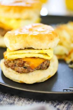 an egg and cheese breakfast sandwich is on a black plate next to some other food items