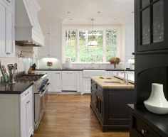 a kitchen with white cabinets and black counter tops is seen in this image from the doorway