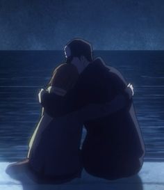 two people sitting next to each other in front of the ocean at night with their arms around each other