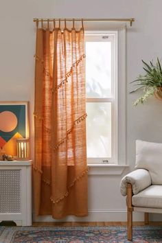 a living room with a chair, window and potted plant