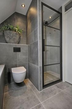 a bathroom with a toilet, shower and planter in the corner on the wall