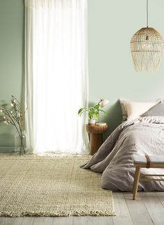 a bedroom with a bed, chair and rug on the floor in front of a window