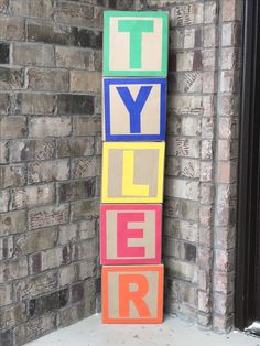 colorful blocks spelling the word tyler in front of a brick wall