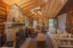 a living room filled with furniture and a fire place next to a stone wall covered in wood