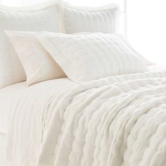 a bed with white sheets and pillows in a room