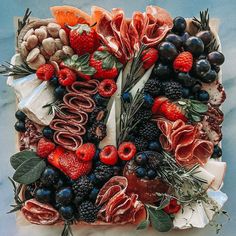 a platter with fruits, meats and vegetables arranged on top of each other