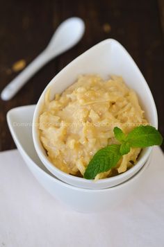 a white bowl filled with macaroni and cheese on top of a table next to a spoon