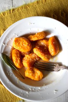 a white plate topped with fried food on top of a yellow table cloth next to a fork