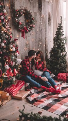 a man and woman sitting next to a christmas tree