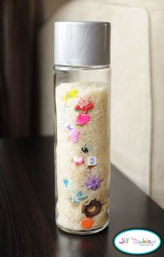 a water bottle that has been decorated with flowers and buttons on the side, sitting on a table