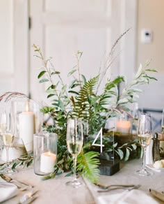 the table is set with candles and greenery