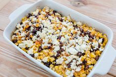 a casserole dish filled with corn, black beans, and feta cheese