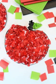 an apple made out of red tissue paper surrounded by other pieces of green and red construction paper