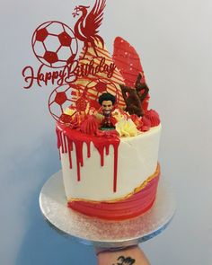 a hand holding a birthday cake decorated with an image of a soccer player