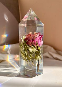 a clear vase with flowers in it sitting on a white tablecloth covered bed sheet