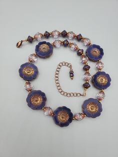 "This necklace and earring set is very beautiful and one of my favorites of all time.  All beads used are glass and manufactured in the Czech Republic.  The hibiscus flowers are purple silk with an antique copper wash.  Setting off those flowers and adding the sparkle, are table cut crystal spiral faceted beads that have a purple copper effect applied.  Pretty purple and copper \"Saturn\" beads are the perfect touch to finish out the beauty of this necklace.  I love Czech glass beads because of Glass Flower Charm Jewelry, Costume Jewelry Flower-shaped Necklace For Gift, Costume Jewelry Flower Shaped Necklace For Gift, Elegant Glass Flower Necklaces, Elegant Flower Shaped Glass Necklaces, Elegant Flower-shaped Glass Necklaces, Gold Glass Flower Jewelry, Gold Flower-shaped Glass Jewelry, Gold Glass Flower Shaped Jewelry