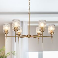 a chandelier hanging from a ceiling in a room with white walls and windows