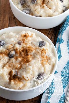 two white bowls filled with mashed potatoes on top of a wooden table next to a blue and white towel