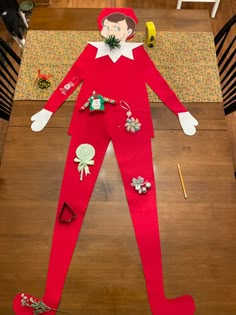 an elf costume made out of paper on top of a wooden table with other items